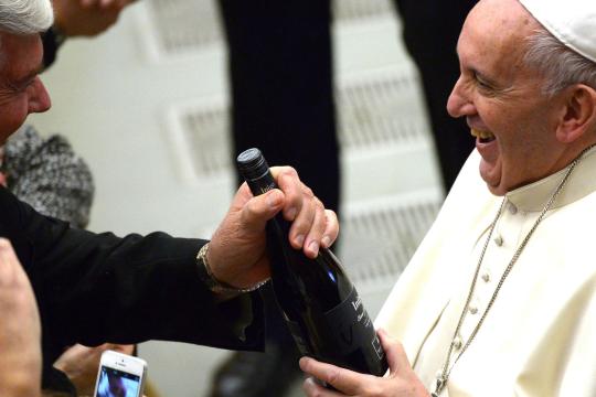 Pope-Francis-is-handed-a-bottle-of-wine-by-a-member-of-the-congre